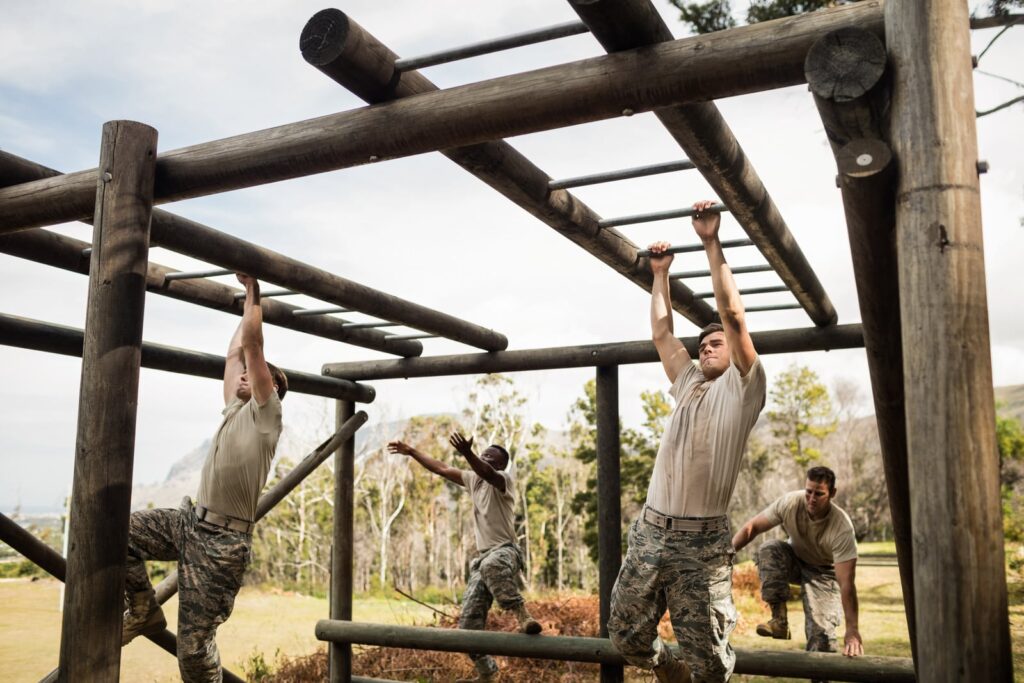 Soldiers training together on monkey bars at boot camp